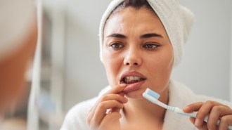 A woman looks at her gums in the mirror.