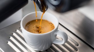 Espresso pours from a machine into a cup.